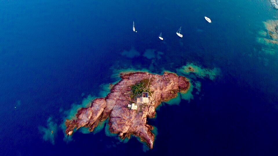 Île rocheuse vue du ciel entourée de voiliers